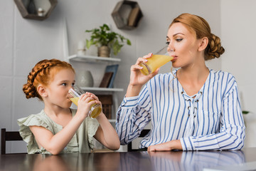 mother and daughter drinking orange juice