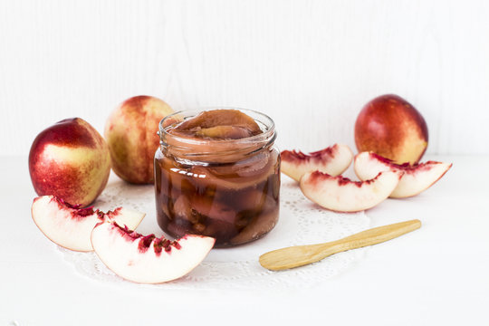 Nectarine jam in a jar next to fresh fruits