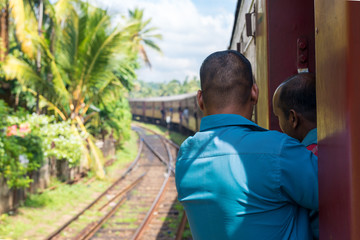 In the railroad car on the way to Colombo. Locals stand in the doors of the rail wagon. The coastal...