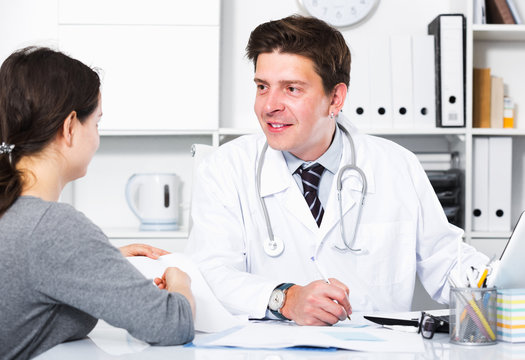 Cheerful professional doctor in uniform talking with patient
