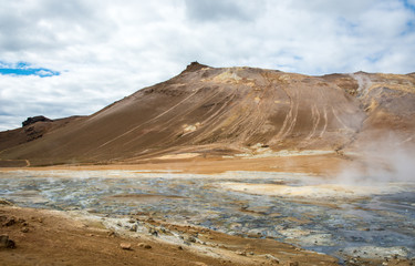 Mudpot in the Namafjall geothermal area, Iceland - area around boiling mud is multicolored and cracked