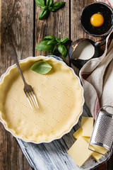 Dough for baking quiche tart in ceramic baking form ready for bake. Ingredients above flour, egg,...