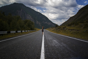 single barefoot woman is walking along the mountain road. Travel, tourism and people concept