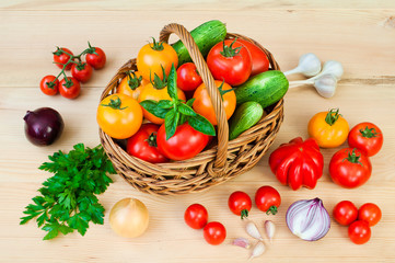 Tomatoes, onions and other vegetables in a wicker basket on a wooden table.