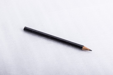 A black pencil, on a white surface.