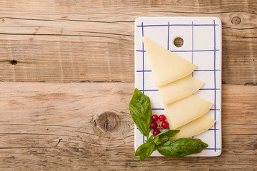 Top view on slices of fresh homemade cheese served with red currant on rectangular plate on wooden board background. Healthy eating, snack.