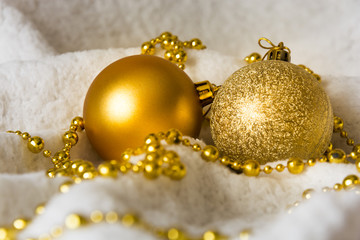 Gold Christmas balls with gold string in the white winter background.