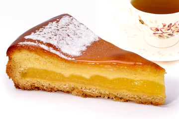 Close up of a slice of lemon cake with cup of tea