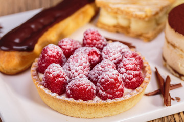 close up shot of Delicious raspberry mini tarts with fresh raspberries and icing sugar