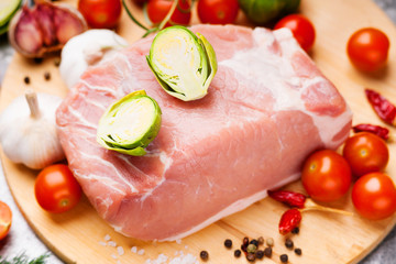 Raw pork on cutting board and vegetables 