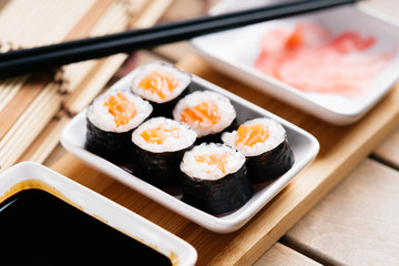 Sushi rolls with salmon, chopsticks and dishes with soy sauce and ginger 