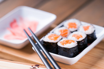 Sushi rolls with salmon, ginger and chopsticks 