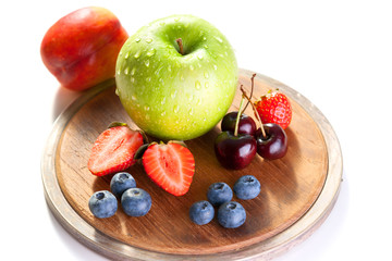 Fresh fruits and berries on a wooden cutting board