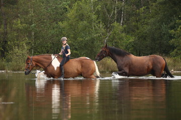 Reiterin durchquert See mit Handpferd