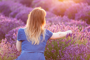 Young woman picking lavender flowers at sunset.