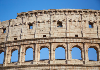 Obraz premium Part of the Colosseum against a blue sky Rome, Italy.