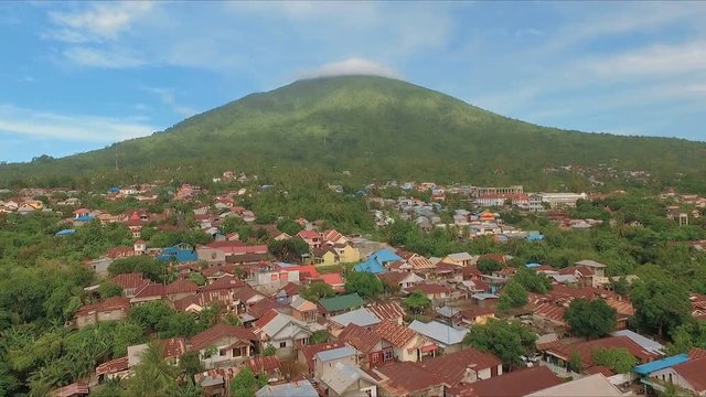 Aerial view of tropical island Ternate with Gamalama volcano in the middle, Indonesia. Shot with drone on sunny day with blue sky, fly forward.