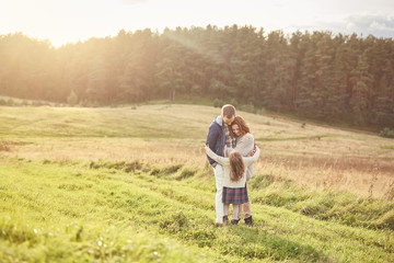 Naklejka premium Family, harmony, relationships concept. Friendly family embracing, having good relationships, resting outdoors, feeling togetherness while being on nature. Young couple and their little daughter