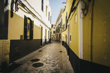 Fototapeta na wymiar Yellow walls on a narrow cobble stones street