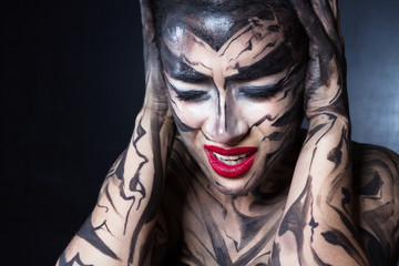 Разукрашенная напряженная женщина закрыла уши руками.