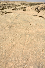 Rocky deserted landscape with ancient dot carvings at Jebel Jassassiyeh site in Northern Qatar.