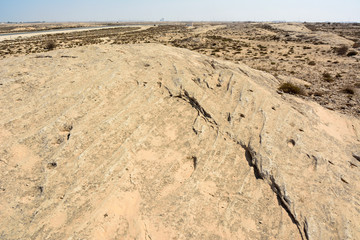 Fototapeta na wymiar Rocky deserted landscape with ancient dot carvings at Jebel Jassassiyeh site in Northern Qatar.