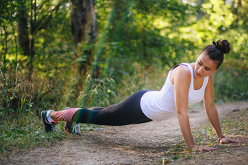 White young girl doing stretching exercises in the forest
