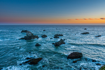 Obraz premium Marvellous sunset, amazing evening sky. Large boulder among the waves in the sea. Sonoma Coast State Park, California, USA