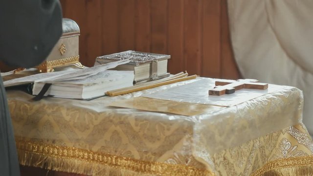 The priest corrects the cross on the table and crosses himself