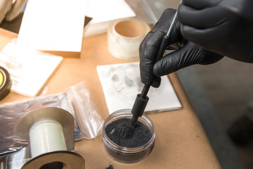 forensic hand in glove brushing latent fingerprints evidence by magnetic powder