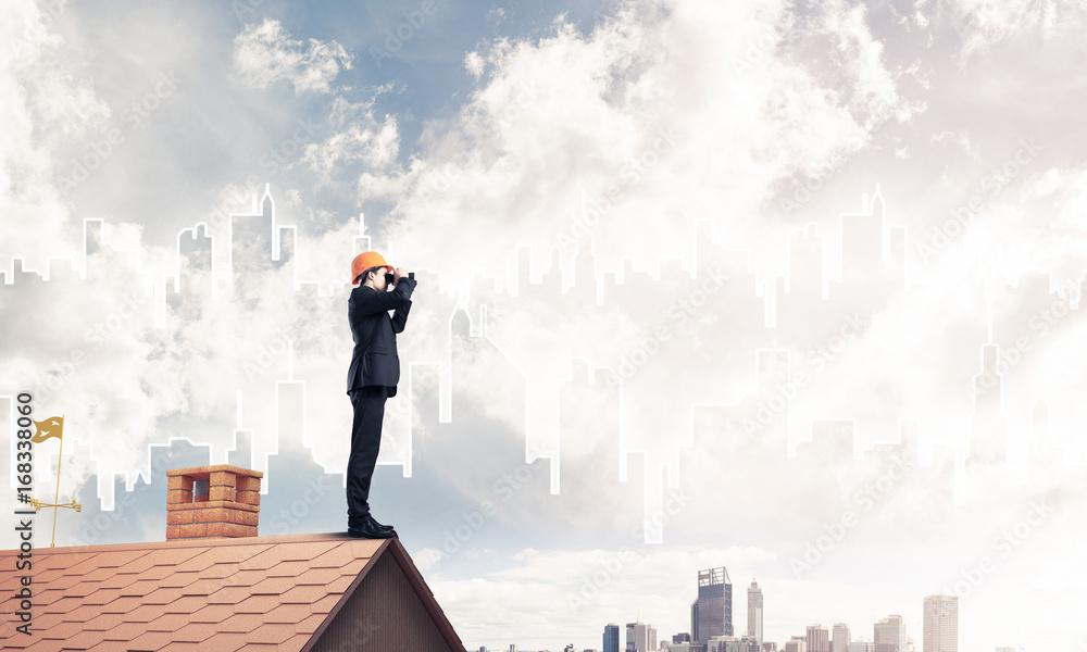 Wall mural engineer man standing on roof and looking in binoculars. mixed m