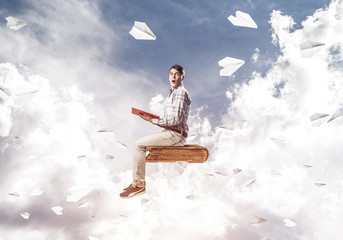 Handsome man student reading book and paper planes flying around