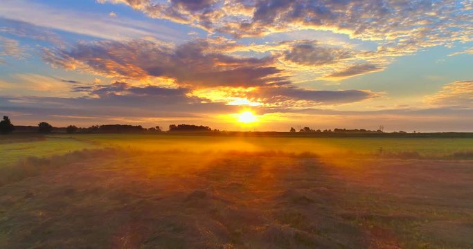 Amazing sunrise bursts through clouds over foggy Midwest farm fields.

