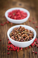 Wooden table with preserved Pink Peppercorns, selective focus