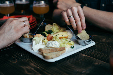 Hands taking snacks from the plate on wooden table