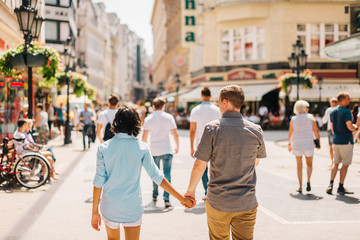 Multicultural Happy Couple Tourists Walking Down The Street Holding Hands | Honeymoon