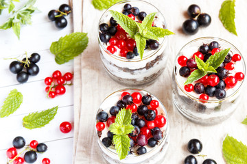 A sweet dessert of sponge cake with cream in a glass with fresh berries on wooden background