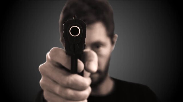 Man Pointing Gun At Cam. Man pointing a gun straight to the camera on a black background