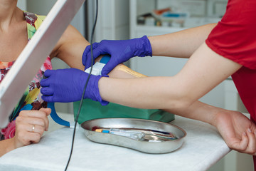 Nurse preparing patient to do a blood analysis by fixing garrot on her arm
