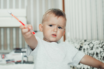 Little baby boy thoughtfully draws or writes pen