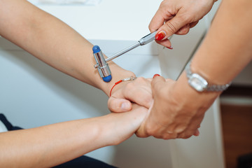 The neurologist testing reflex on a female patient using a hammer