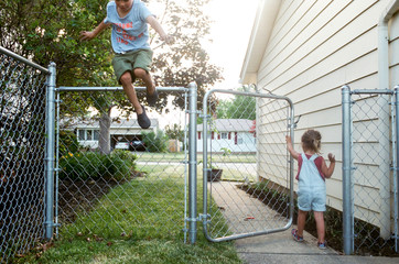girl walks out fence while brother jumps