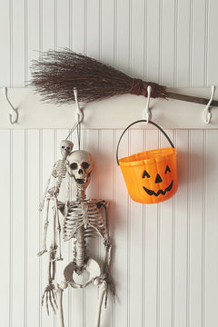 Toy skeletons and candy bucket hanging on coat hook