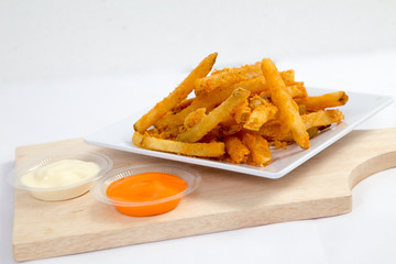 Hot and spicy french fries on a white plate with mayonnaise and cheese sauce