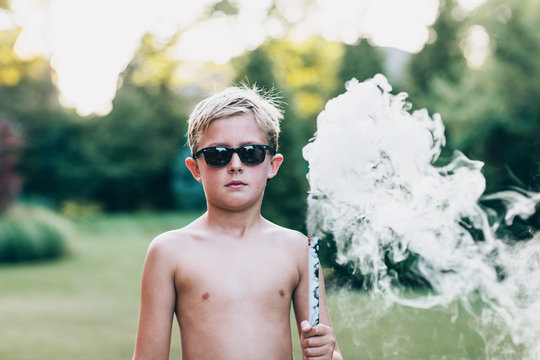 boy holding a smoke bomb on a summer evening