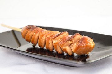 Grilled sausage on black plate and white background