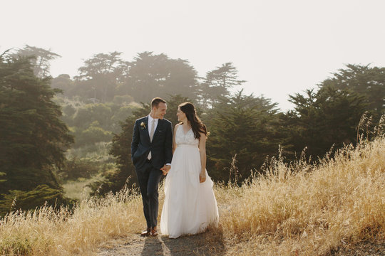 Bride and Groom Walking through Field