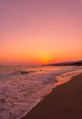 Blick auf menschenleeren Strand im warmen Licht eines Sonnenaufgang 