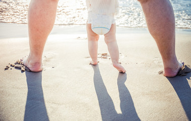 Obraz na płótnie Canvas Close up of father and little baby feet on beach