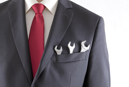 Businessman with three spanners in suit pocket isolated on white